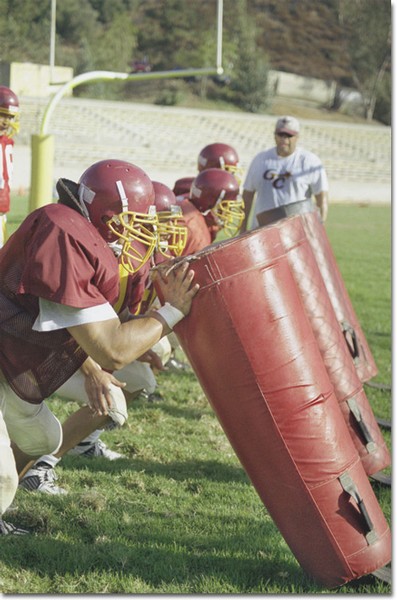 Coach Jesse Garcia instructs the defensive line as they plow through their drill.