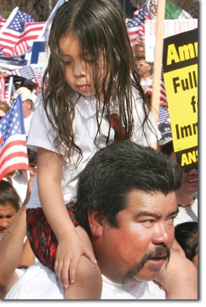 A little girl is carried on the arms of a relative. They were among the thousands of protestors marching down  Wilshire Boulevard on May 1.