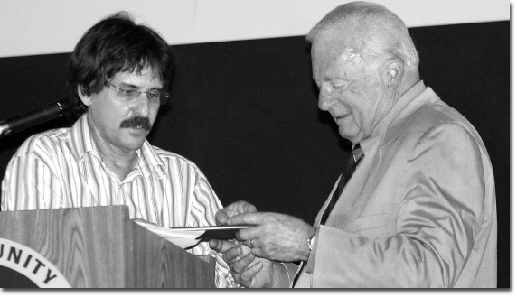 Sid Kolpas presents John Davitt with a special commemorative stamp collection featuring the likeness of the president/superintendant himself.