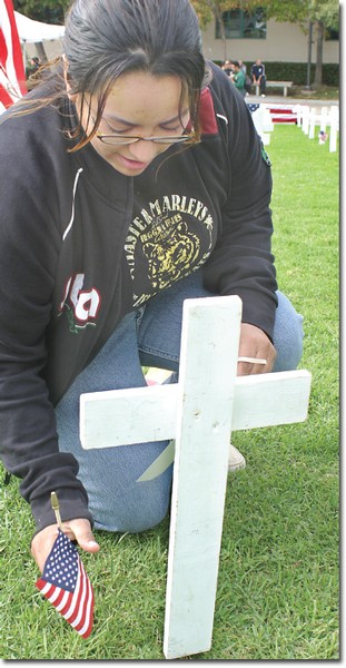 Vanessa Salgado, 18, an international business major, at left, places a flag at a symbolic grave site on Nov. 8 during the Arlington West
demonstration.