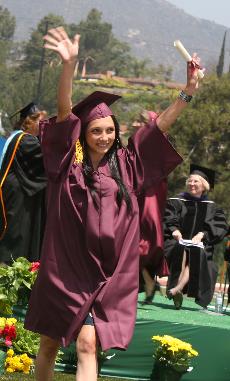 An ecstatic graduate waves to the crowd.