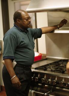 Lew Lewis inspects a vent hood in the culinary arts department. Layoffs mean less staff for maintenance.