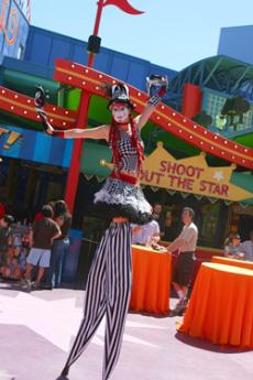 A circus sideshow stiltwalker entertains the crowd.