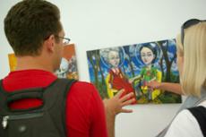 Students admire and discuss artwork during the current exhibit in the campus art gallery on May 14.