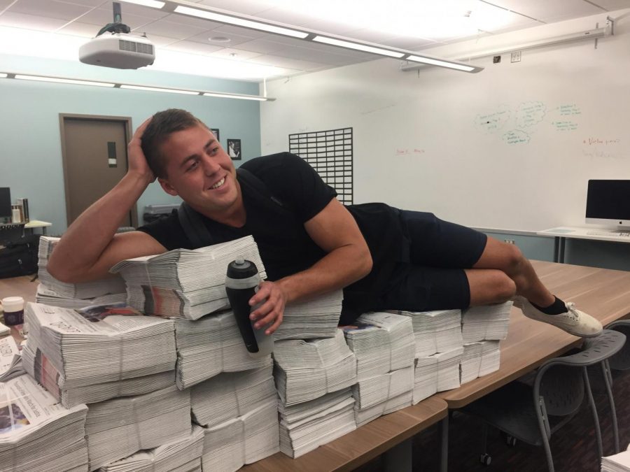 Ken Allard poses on top of a stack of newspapers unexpectedly during the spring 2018 semester.