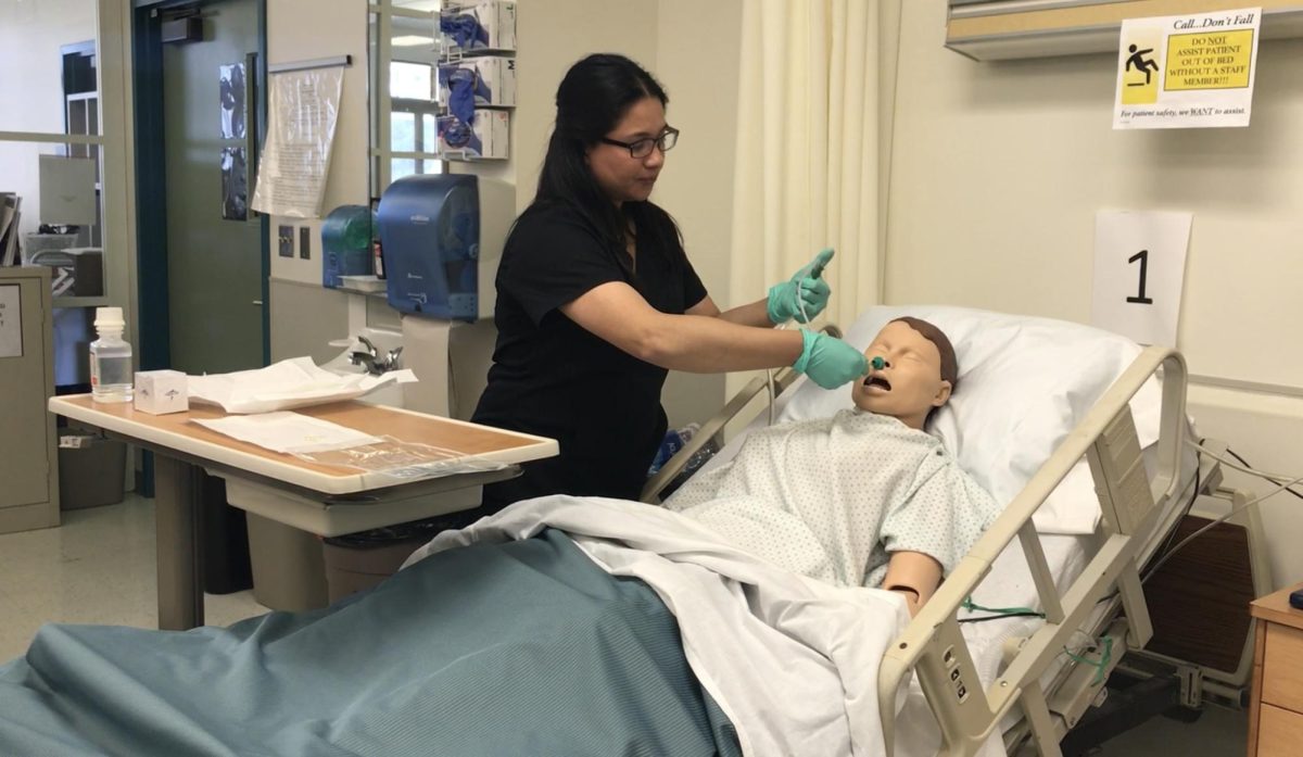 Interim Associate Dean Michelle Ann Ramirez demonstrates a suctioning skill at the college's Nursing Resource Lab in the Health Sciences Building.